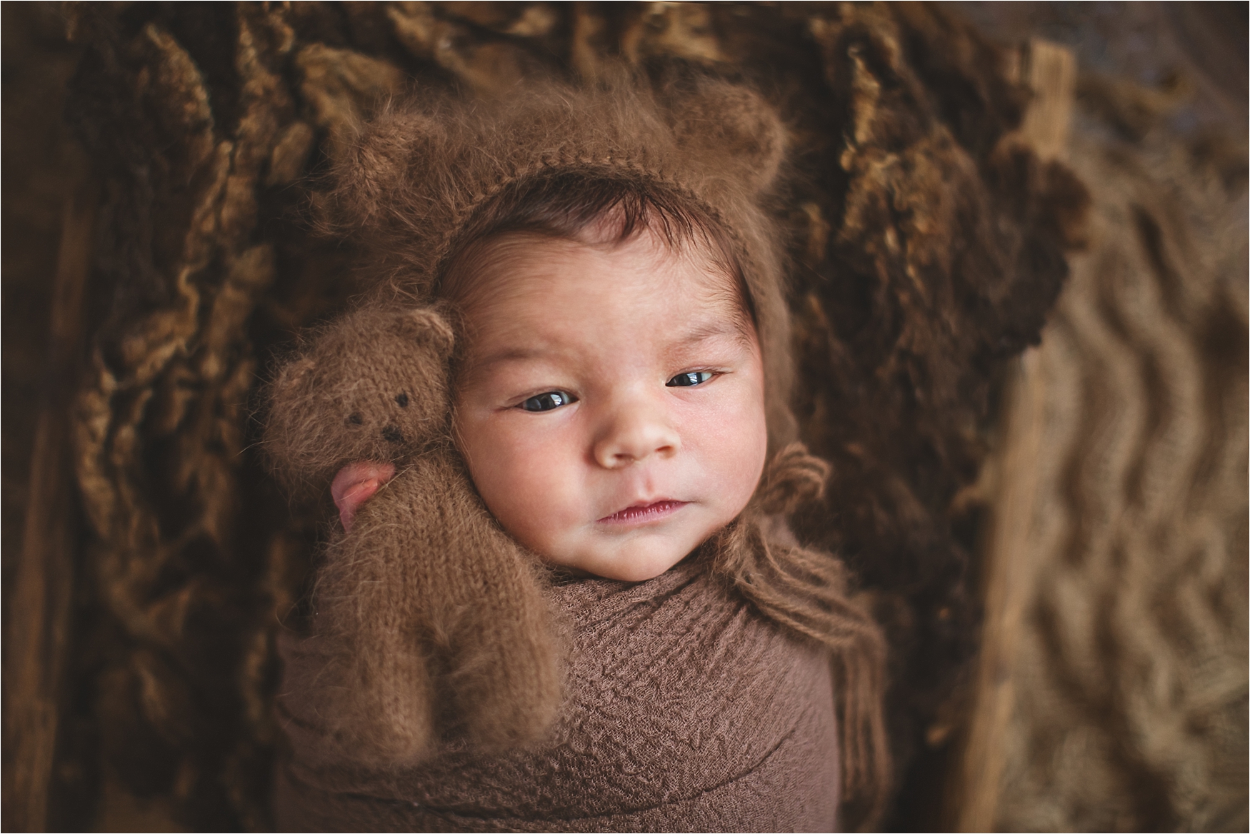 newborn baby boy in beautful browns holding a stuffed brown teddywear