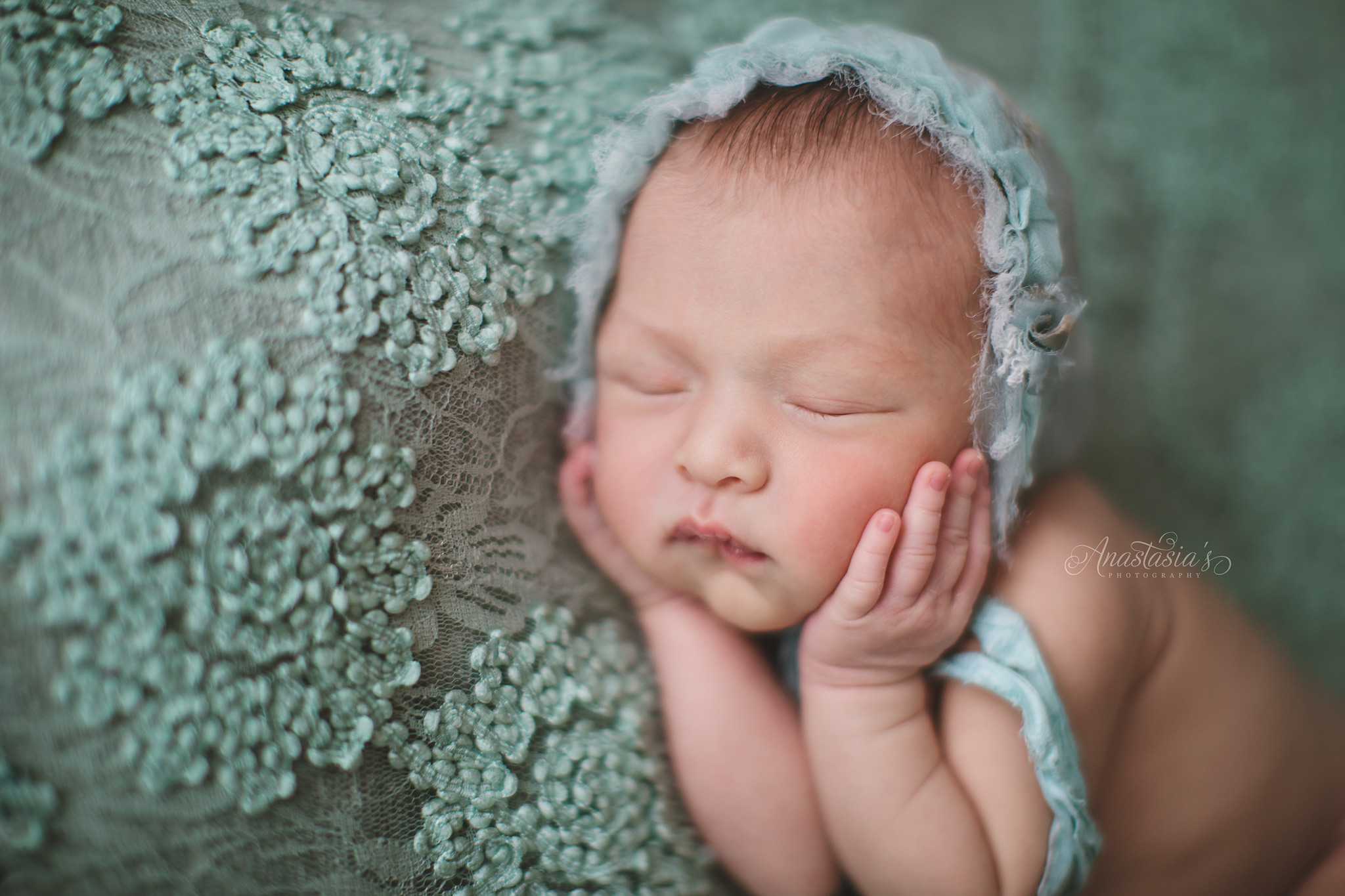 newborn girl angel in mint green with hands to her face